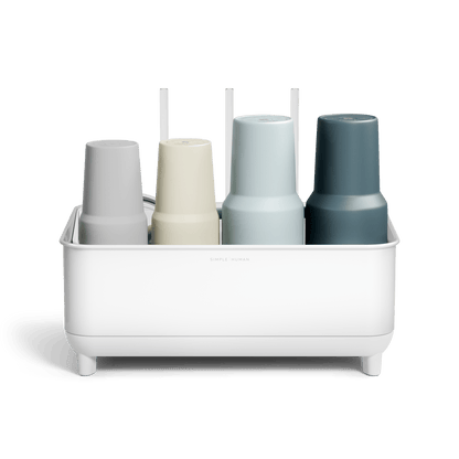 Front view of Simplehuman White Bottle Dock holding four reusable bottles in assorted colors with straws in the background.